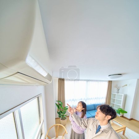 Photo for A man in work clothes standing in front of an air conditioner and a woman watching over it - Royalty Free Image