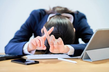 Eine Frau im Anzug, die am Schreibtisch arbeitet, sieht müde aus