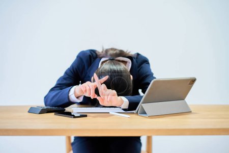 Téléchargez les photos : Une femme en costume travaillant à un bureau a l'air fatiguée - en image libre de droit