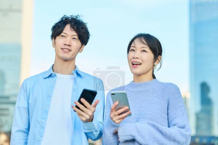 Photo for Smiling man and woman with smartphone in hand on fine day - Royalty Free Image