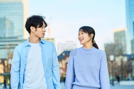 Téléchargez les photos : Jeune homme et femme marchant côte à côte à travers la ville - en image libre de droit