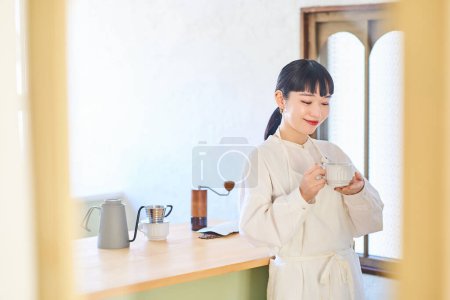 junge Frau mit Kaffeetasse in der Küche