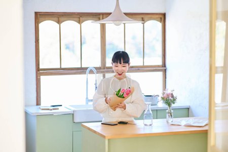 Téléchargez les photos : Jeune femme appréciant les fleurs dans un vase dans la chambre - en image libre de droit