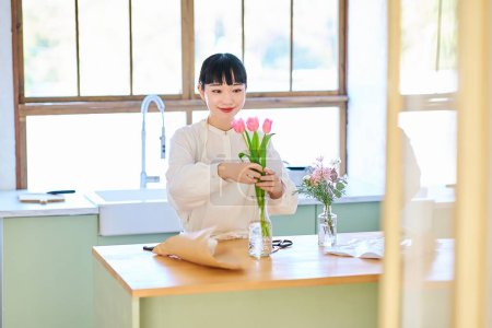 Jeune femme appréciant les fleurs dans un vase dans la chambre