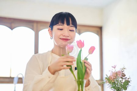 Junge Frau genießt Blumen in einer Vase im Zimmer