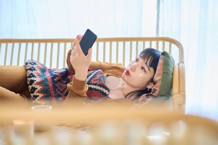 Téléchargez les photos : Jeune femme regardant smartphone tout en dormant - en image libre de droit