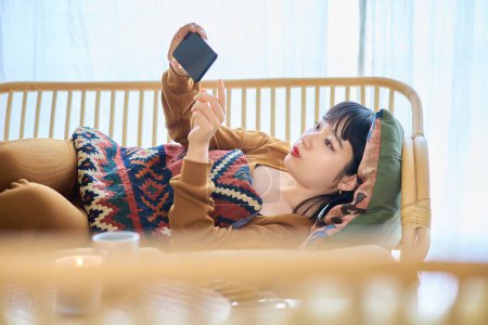 Photo for Young woman looking at smartphone while sleeping - Royalty Free Image