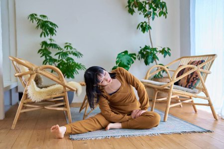 Photo for Young woman doing stretching exercises in the room - Royalty Free Image
