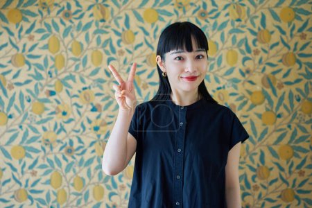Young woman smiling and making peace sign in the room