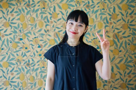 Young woman smiling and making peace sign in the room
