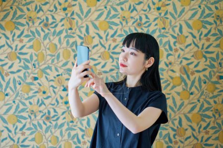 Téléchargez les photos : Jeune femme opérant un smartphone à l'intérieur - en image libre de droit