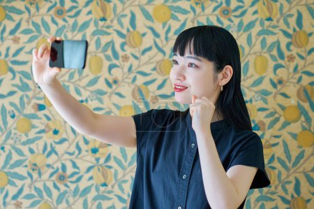 Foto de Mujer joven mirando la pantalla del teléfono inteligente en la habitación - Imagen libre de derechos