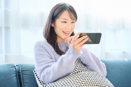 Junge Frau blickt auf Smartphone-Bildschirm im Zimmer