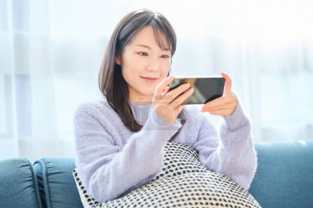 Photo for Young woman looking at smartphone screen in the room - Royalty Free Image