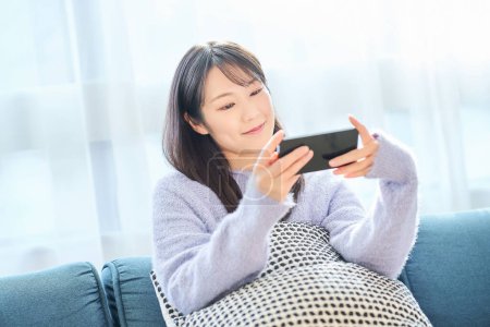 Junge Frau blickt auf Smartphone-Bildschirm im Zimmer