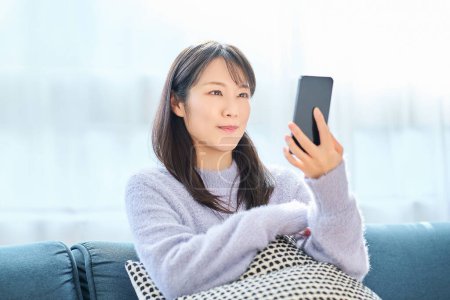 Young woman looking at smartphone screen in the room