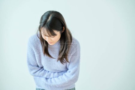A young woman who seems to be suffering from abdominal pain indoors