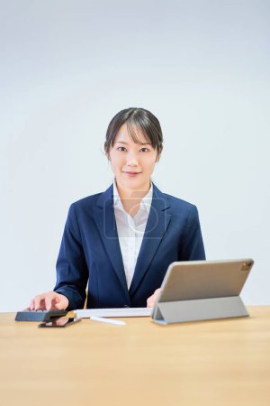 Foto de Una mujer con un traje operando una computadora frente a un fondo blanco - Imagen libre de derechos