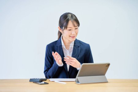 Young woman in suit during online meeting in front of white background