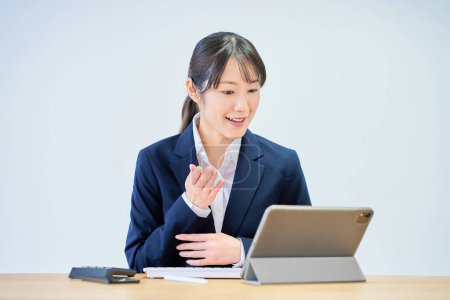 Téléchargez les photos : Jeune femme en costume lors d'une réunion en ligne devant fond blanc - en image libre de droit