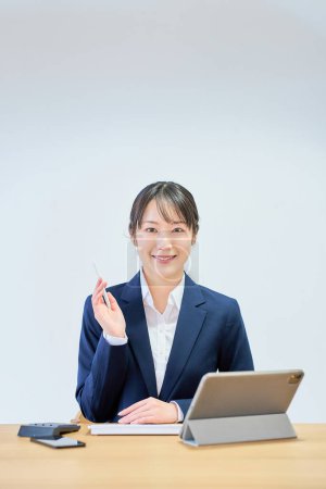 Une femme en costume faisant fonctionner un ordinateur devant un fond blanc