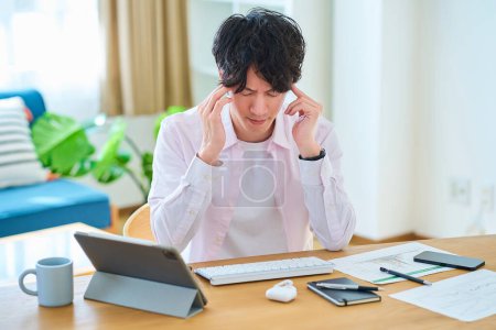 Foto de Un joven se siente estresado mientras opera una computadora en su habitación - Imagen libre de derechos