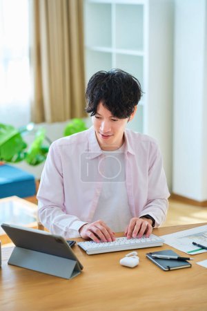 Jeune homme opérant un ordinateur dans sa chambre pendant la journée