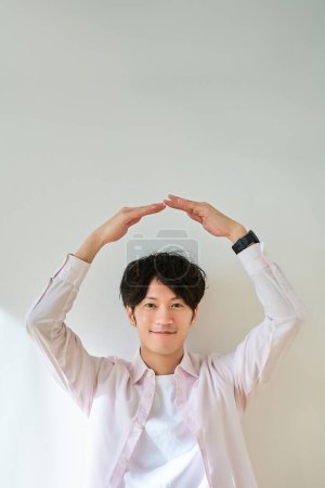 Photo for A young man making an ok hand sign in front of a white background - Royalty Free Image
