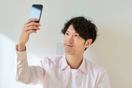 Young man looking at smartphone screen in front of white background