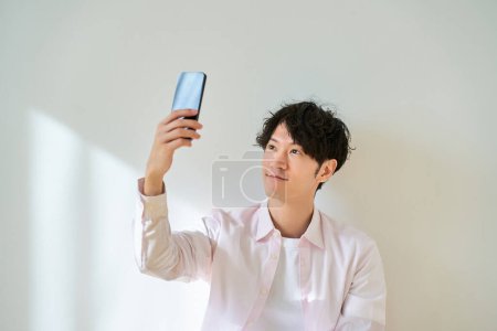 Young man looking at smartphone screen in front of white background