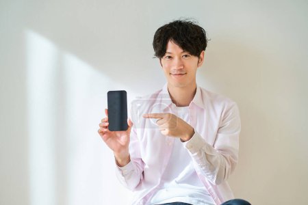 Téléchargez les photos : Jeune homme tenant un smartphone à l'intérieur - en image libre de droit