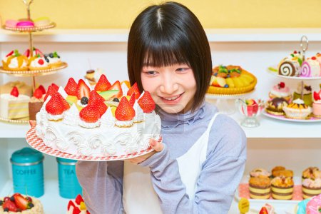 Téléchargez les photos : Une jeune femme tenant un gâteau entier dans la chambre - en image libre de droit