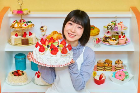 Téléchargez les photos : Une jeune femme tenant un gâteau entier dans la chambre - en image libre de droit