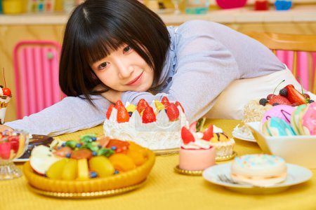 Téléchargez les photos : Une jeune femme entourée de bonbons dans la chambre - en image libre de droit