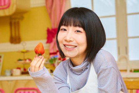 Téléchargez les photos : Une jeune femme mangeant des fraises dans la chambre - en image libre de droit