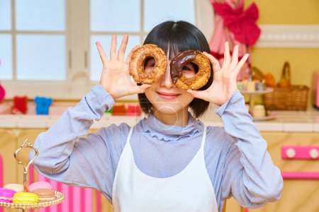 Foto de Joven mujer sosteniendo donuts en la habitación - Imagen libre de derechos