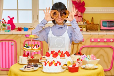 Foto de Joven mujer sosteniendo donuts en la habitación - Imagen libre de derechos