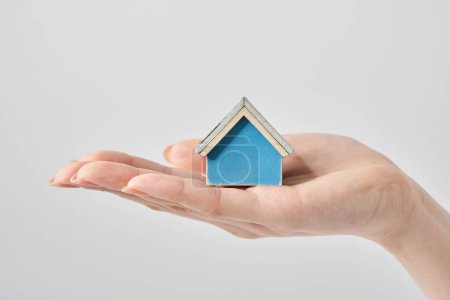 A house model held in the palm of a woman's hand and white background