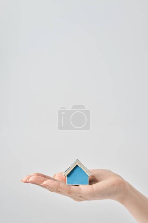 A house model held in the palm of a woman's hand and white background