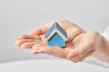 Téléchargez les photos : Un modèle de maison tenu dans la paume de la main d'une femme et fond blanc - en image libre de droit