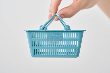 Hand of a woman holding a small shopping basket