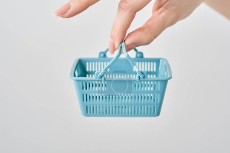Photo for Hand of a woman holding a small shopping basket - Royalty Free Image