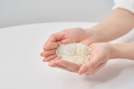Eine Tasse Reis in der Hand und weißer Hintergrund