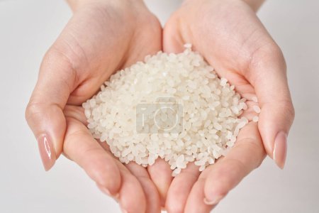 Una taza de arroz en la mano y fondo blanco