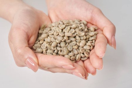 Mano de mujer sosteniendo granos de café antes de asar