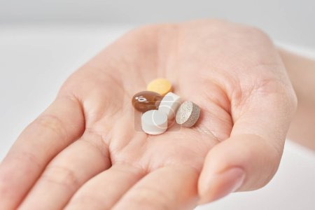 Verschiedene Pillen auf der Hand und weißer Hintergrund