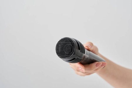 Photo for Woman's hand holding a wireless microphone and white background - Royalty Free Image