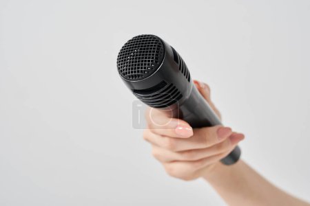 Foto de Mano de mujer sosteniendo un micrófono inalámbrico y fondo blanco - Imagen libre de derechos