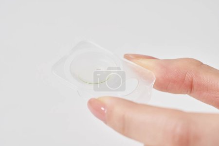 woman's fingers with contact lenses and white background