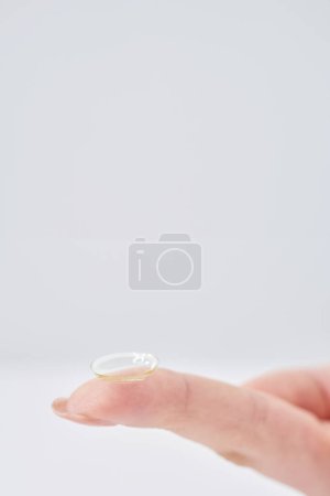 doigts de femme avec lentilles de contact et fond blanc
